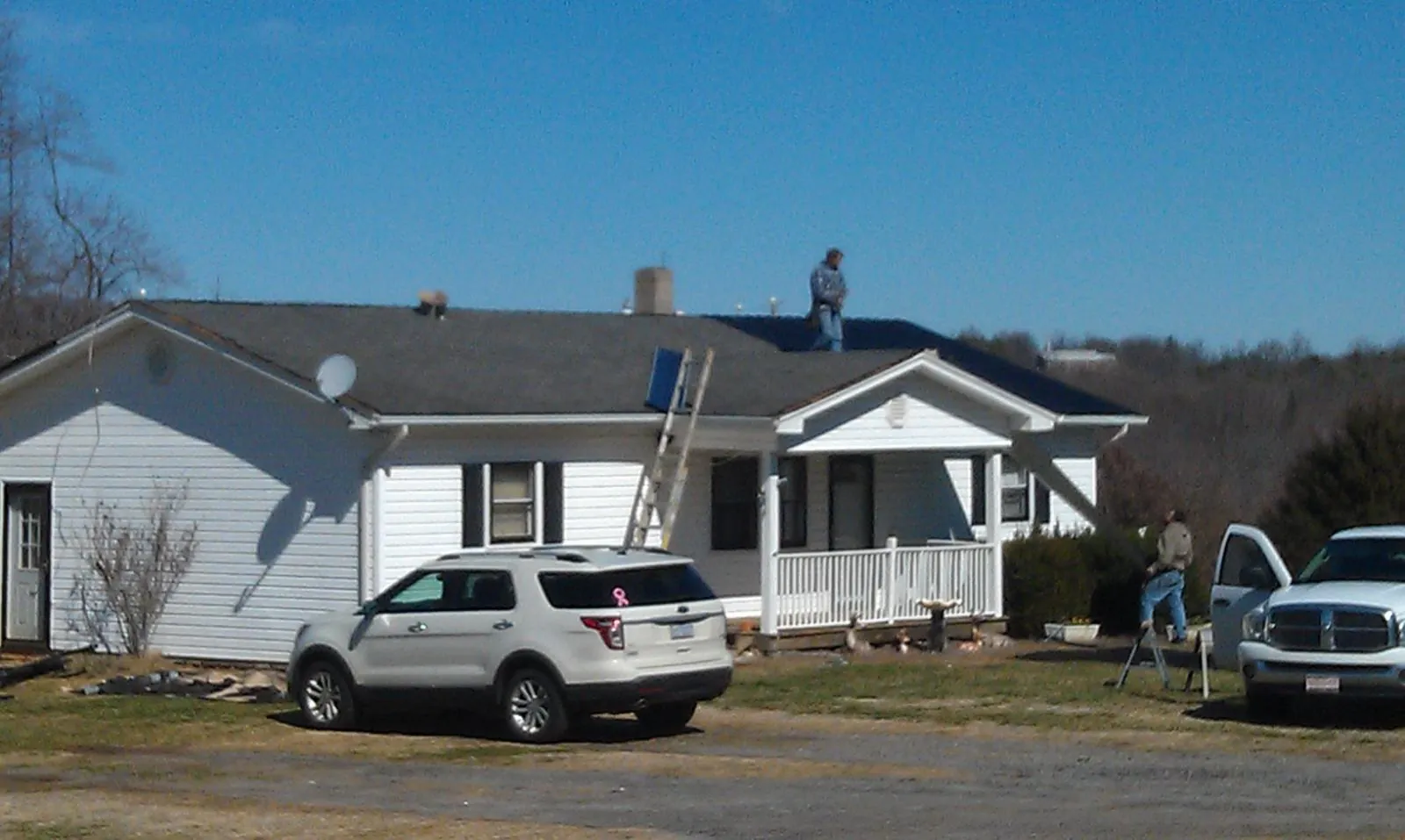 Roofers stripping shingles from a white ranch house roof in Plymouth